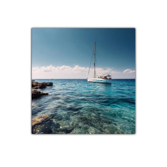 Velero navegando en aguas cristalinas bajo cielo despejado